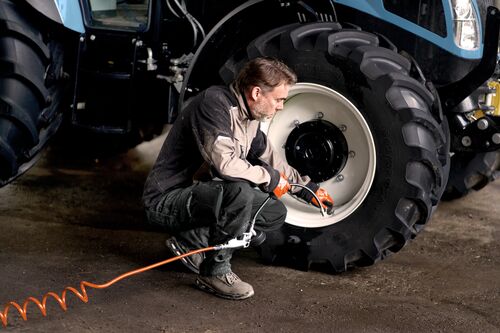 Small STEP RGB Web-Worker is using a Tire filler at a tractor to adjust the air.jpg